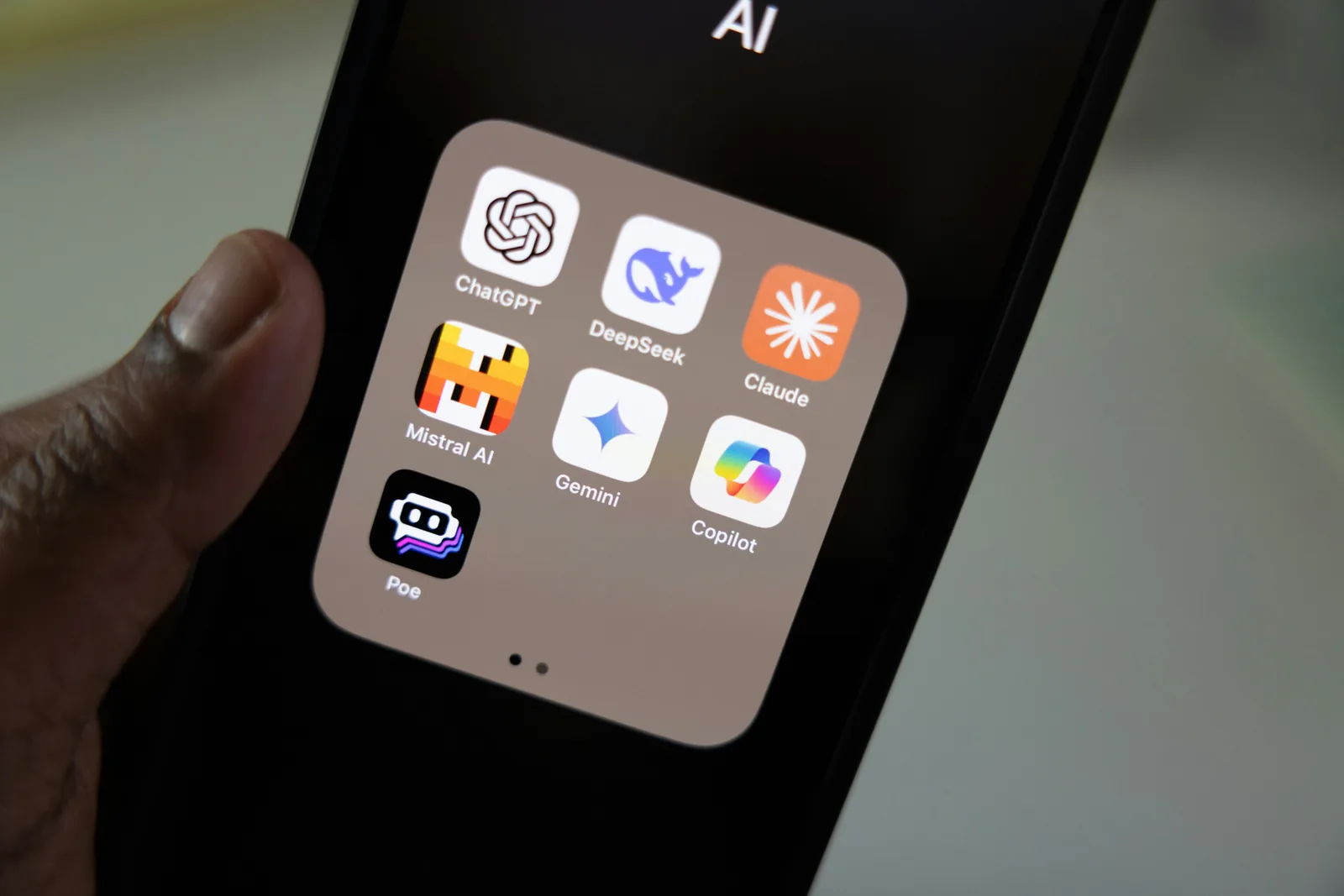 Smartphone-Bildschirm mit einem AI-Ordner: die App-Symbole von ChatGPT, DeepSeek, Claude, Mistral AI, Gemini, Copilot und Poe